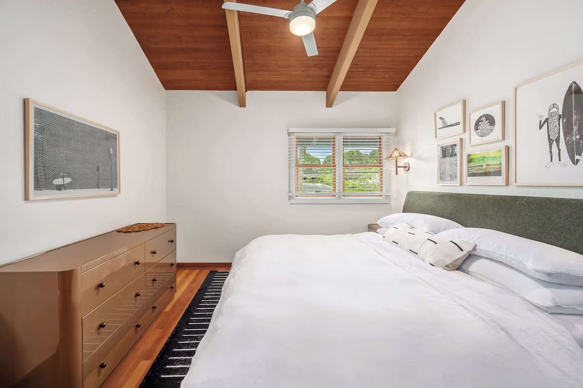 Guest bedroom with a green upholstered headboard, gallery wall and valley window.