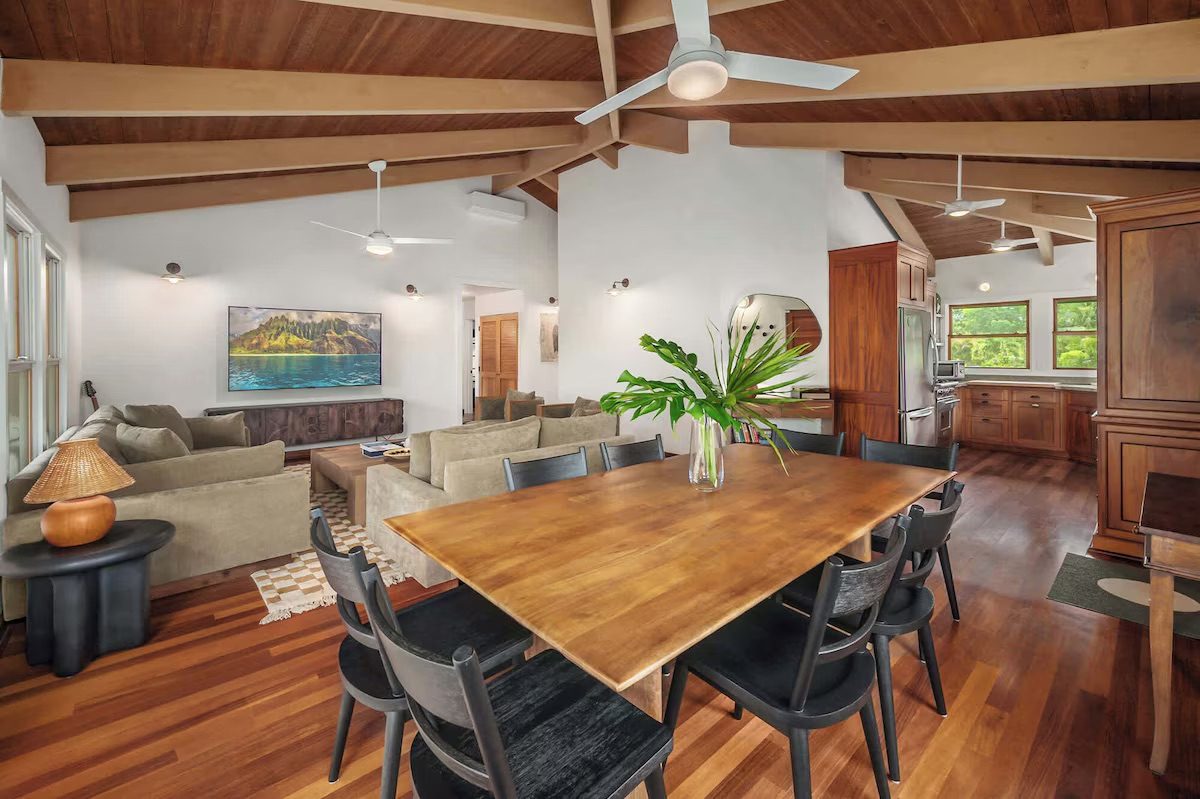 Wide view across the living room and dining table through to the kitchen beyond.
