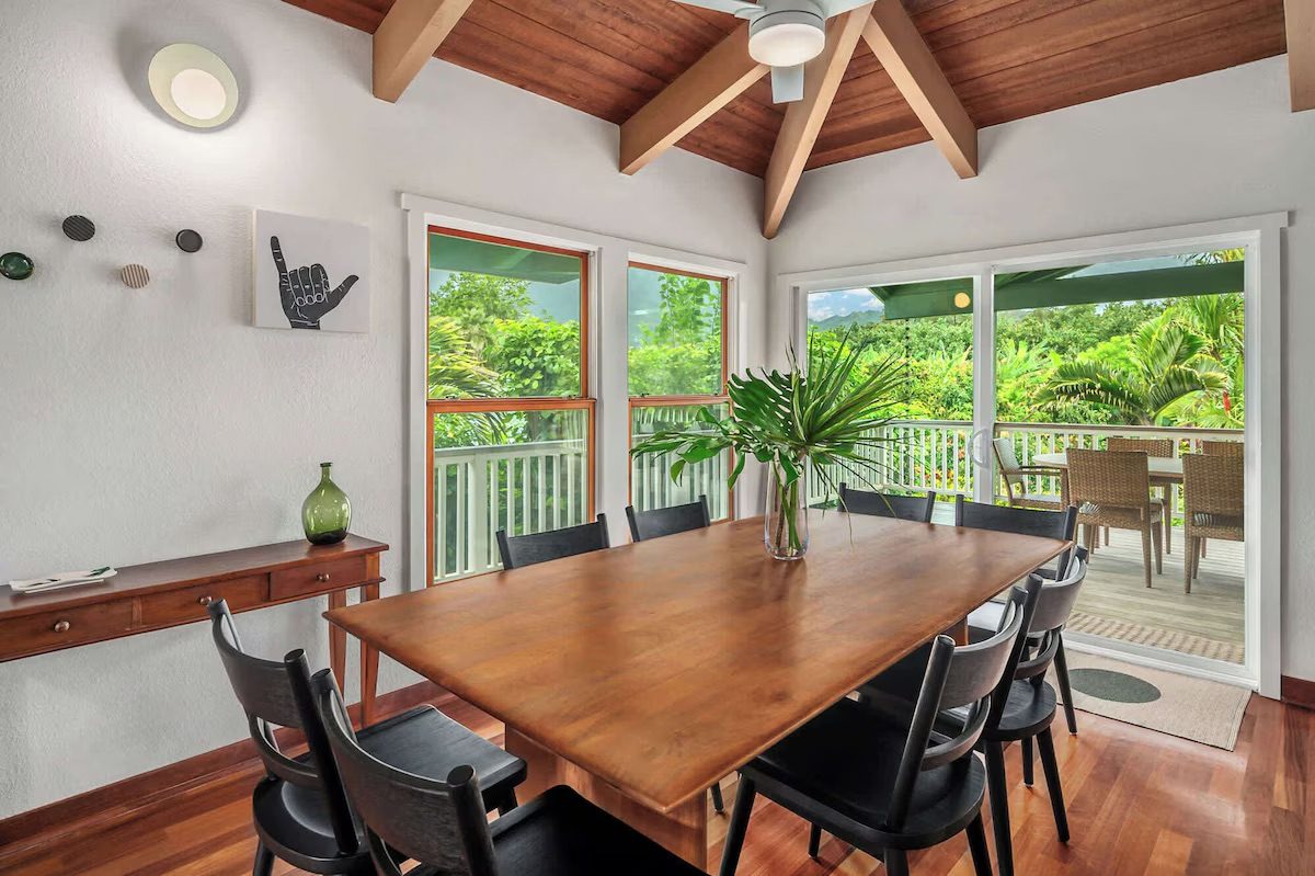 Solid wood dining table with black spindle chairs, open to the lanai doors.
